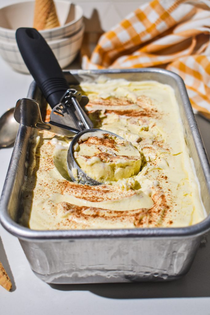 Side view of no churn sweet corn ice cream in a loaf pan with an ice cream scoop.