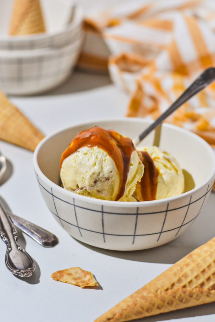 Sweet corn ice cream in a bowl with caramel sauce on top.