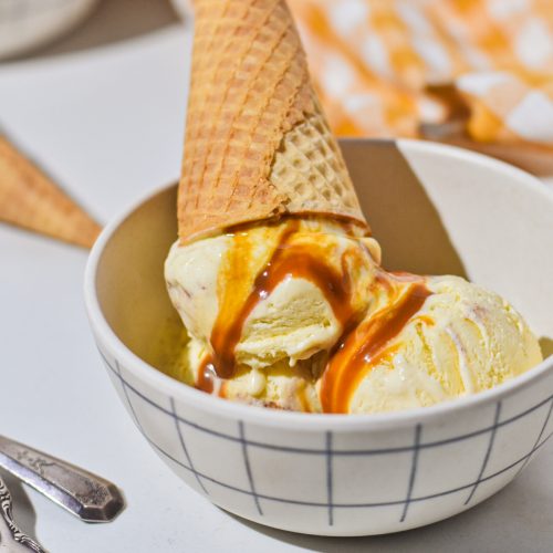Sweet corn ice cream in a bowl with a cone on top.