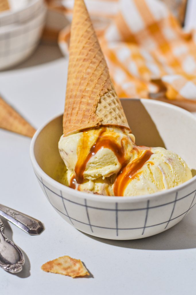 Sweet corn ice cream in a bowl with a cone on top.