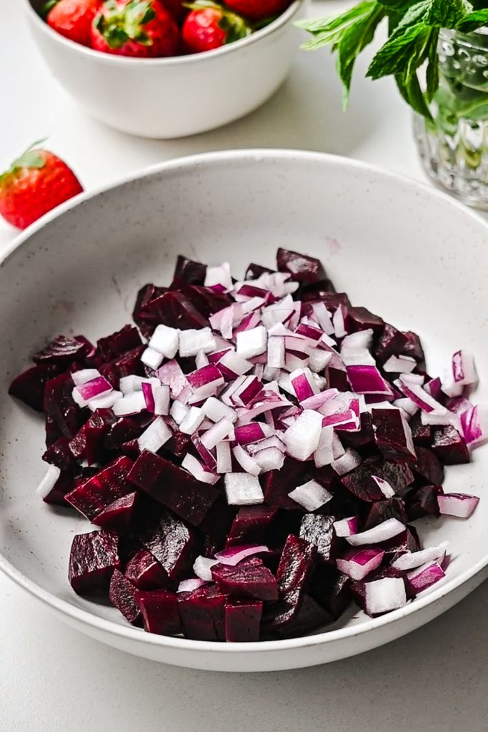 Diced beets and red onions in a white bowl.