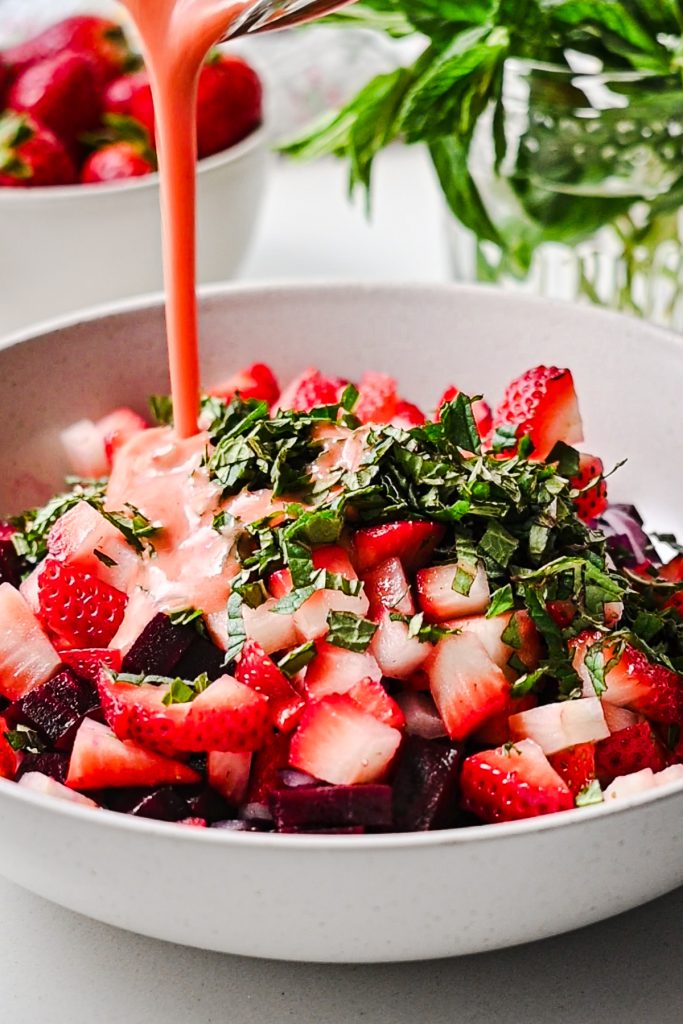 Pouring the strawberry balsamic vinaigrette on top of the beets and strawberries.