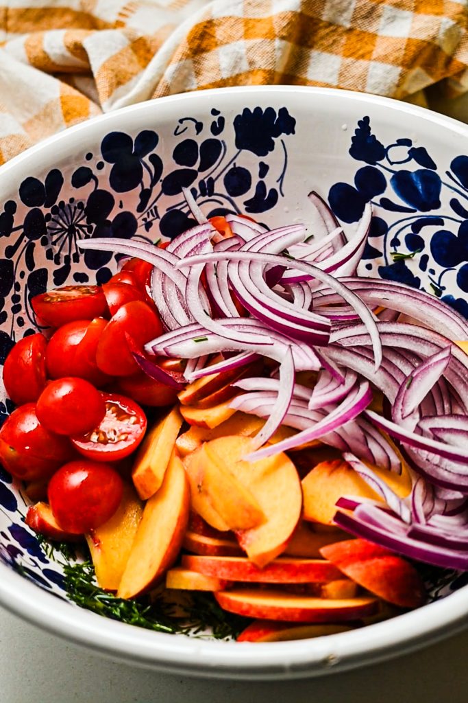 Sliced vegetables added on top of the dill dressing in a salad bowl.