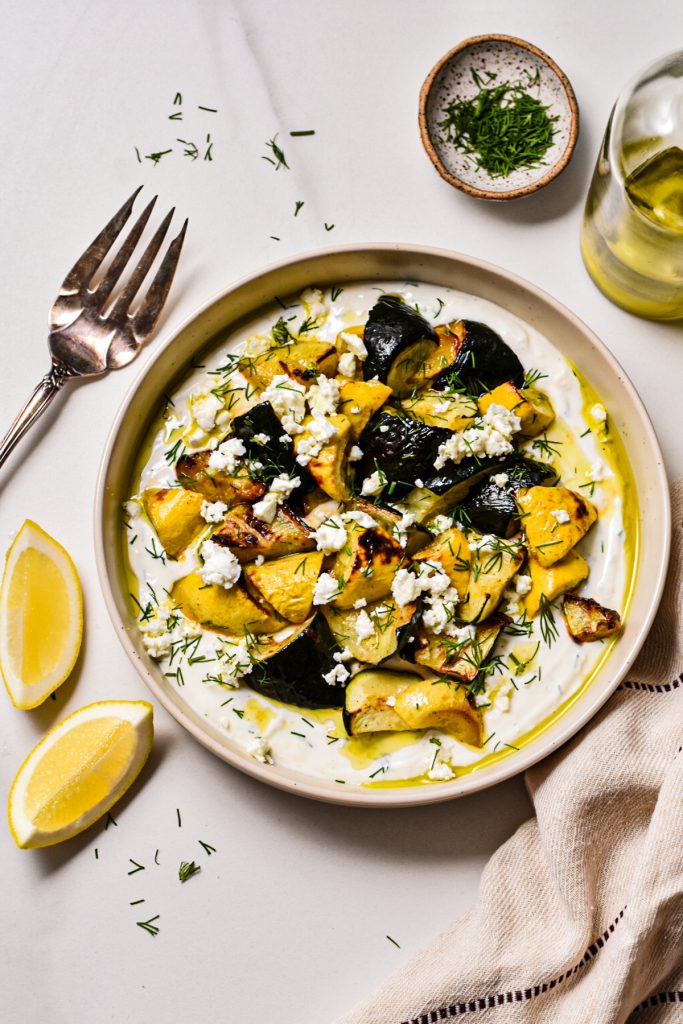 Overhead shot of roasted zucchini on a bed of dill yogurt sauce.