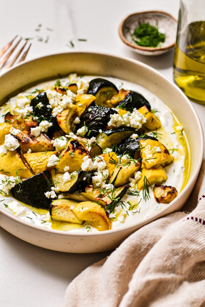 Side view of roasted zucchini and dill yogurt sauce with feta and dill on top.