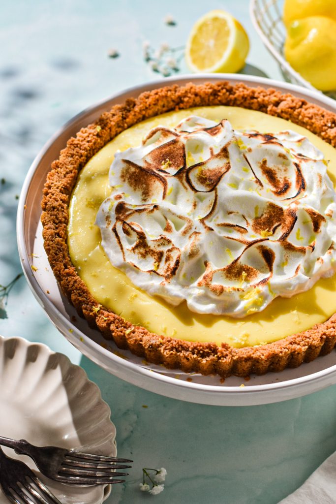 Side view of lemon tart with meringue on top on a white platter.
