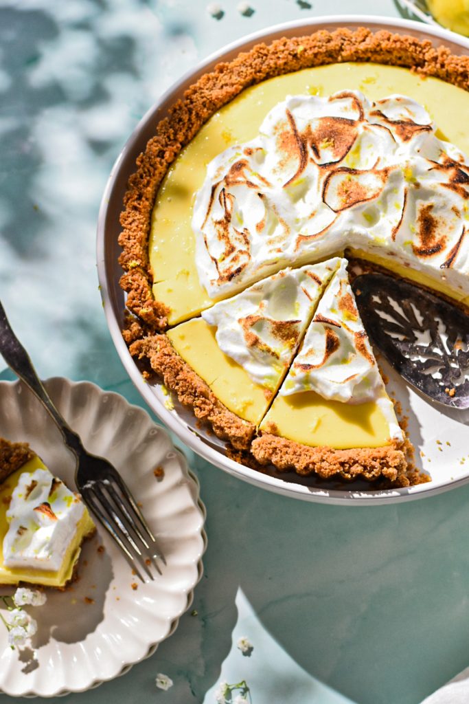 Overhead shot of the lemon tart with some of it sliced and one slice on a plate.