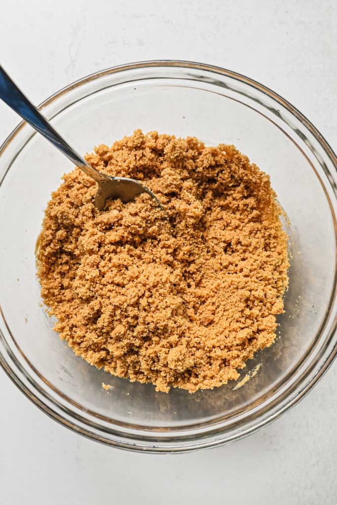 Graham cracker crumbs mixed with sugar and butter in a bowl.