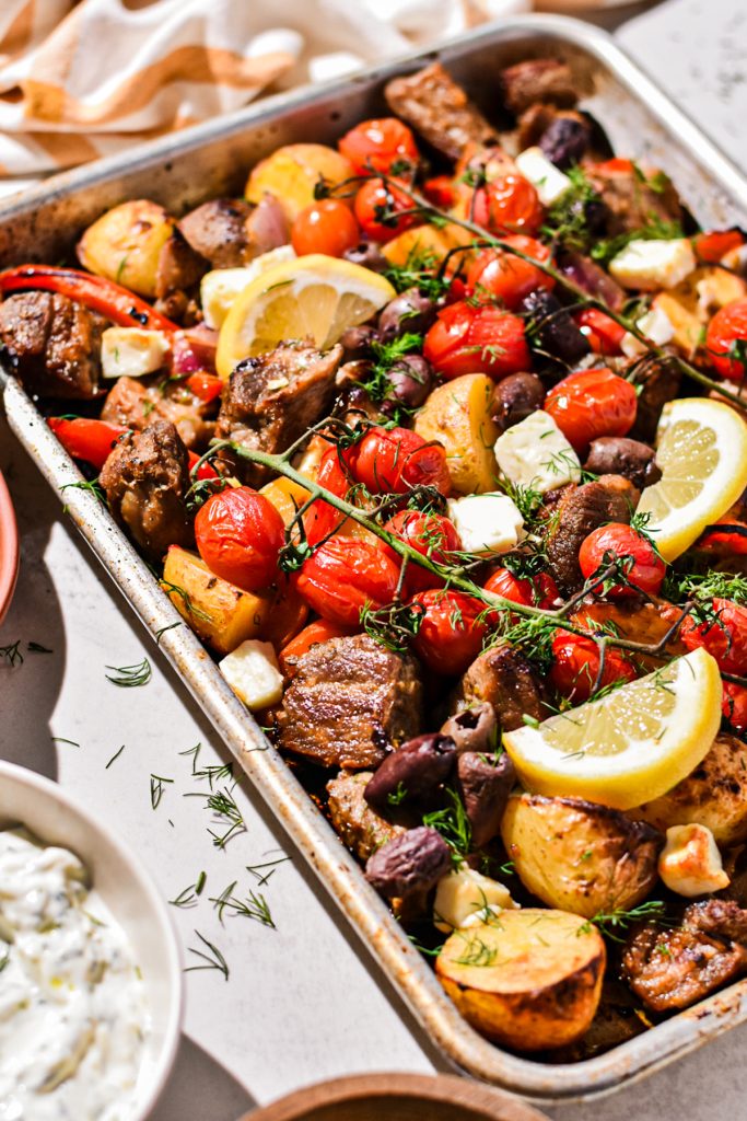 Sheet pan pork souvlaki with lemon, feta and dill on top.