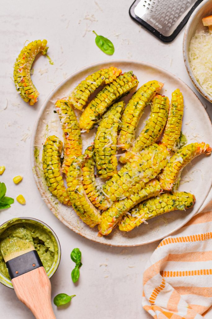 Overhead shot of pesto butter corn ribs on a plate topped with parmesan cheese.