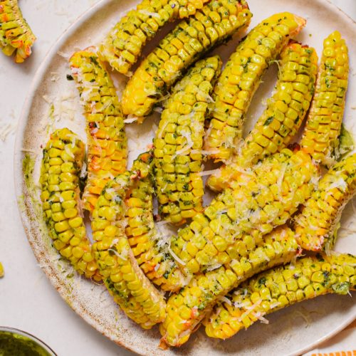 Pesto butter corn ribs on a plate topped with parm.