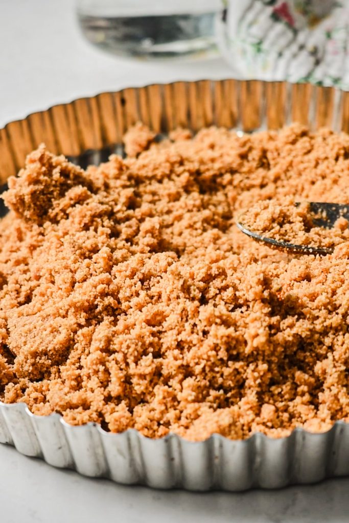 Graham cracker crumbs in the tart pan before pressing it down.