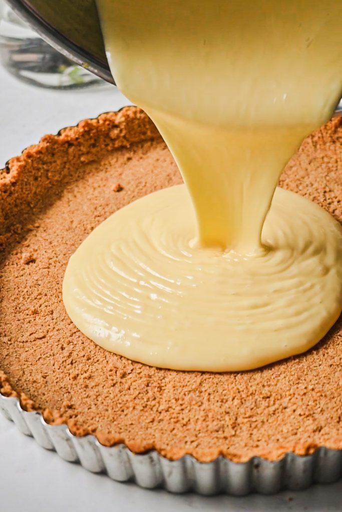 Pouring the lemon curd into the tart crust.