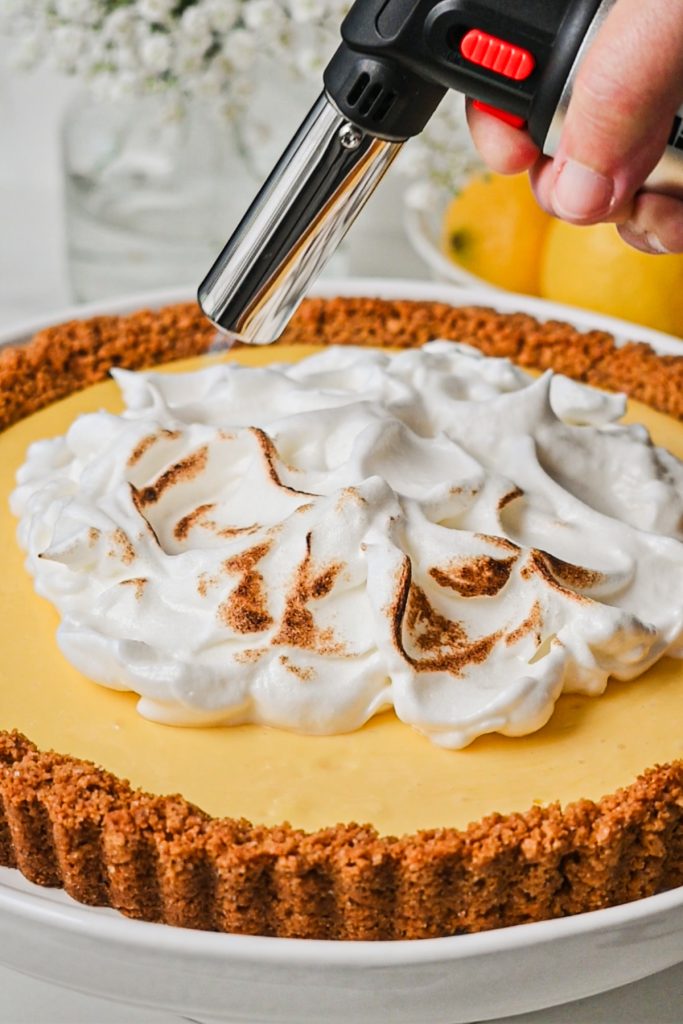 Using a torch to crisp up the meringue on top of the lemon tart.