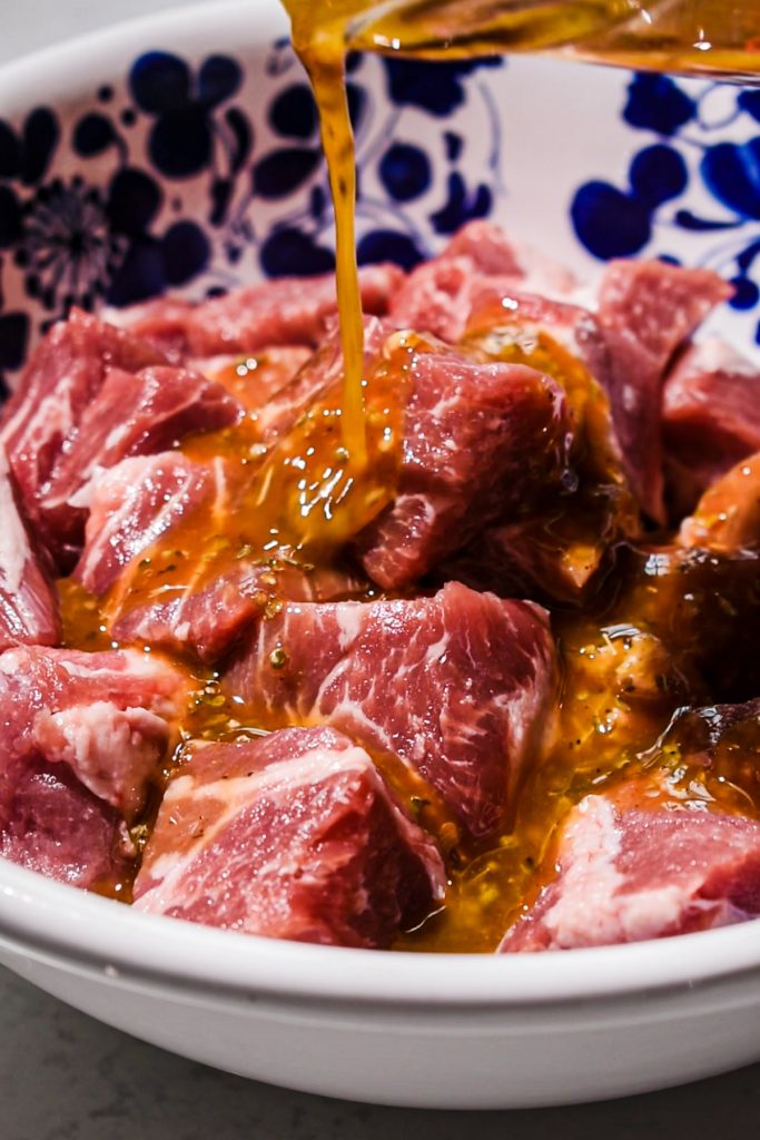 Pouring the marinade over the pork in a mixing bowl.