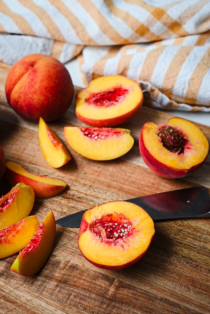 Slicing fresh peaches on a wooden cutting board.