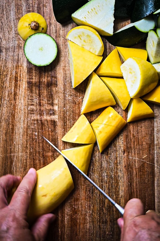 Chopping zucchini and squash on a wooden board.