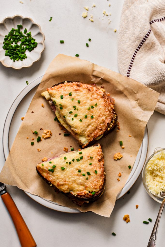 Overhead shot of the croque monsieur cut in half on a plate with parchment paper.