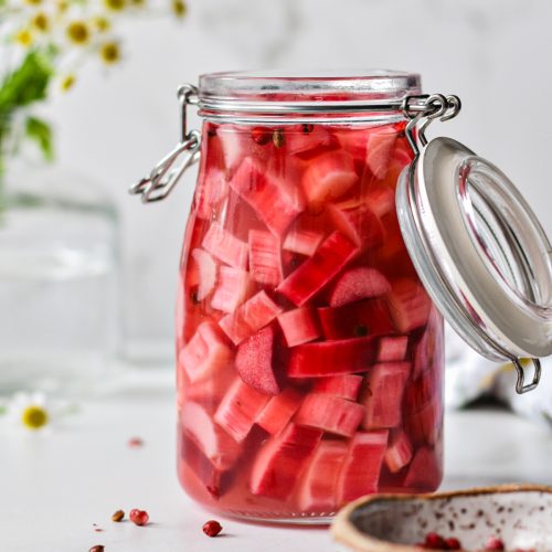 Side view of pickled rhubarb in a large jar.