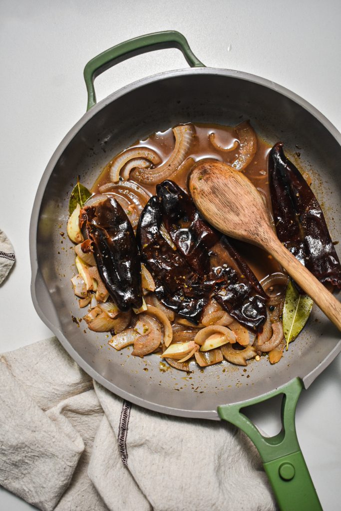 Dried guajillo peppers added to the simmering aromatics to soften.