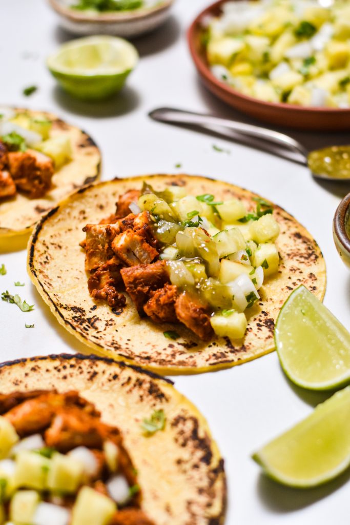 Side view of a chicken al pastor taco with pineapple salsa and salsa verde.