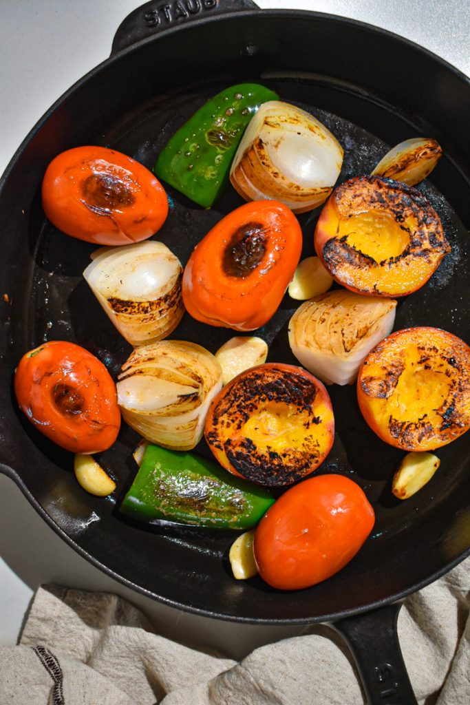 Peaches, onions, tomatoes, jalapeño and garlic in a cast iron skillet to char.