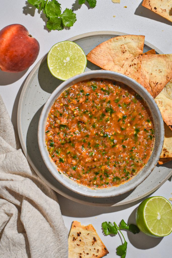 Grilled peach and tomato salsa in a bowl with tortilla chips on the side.