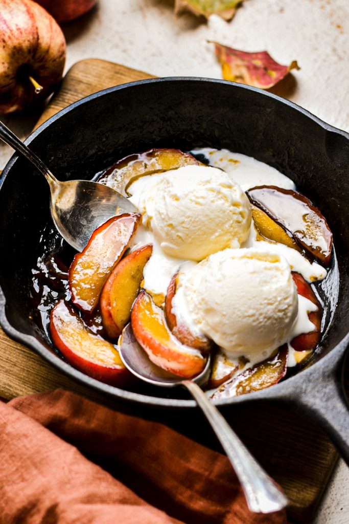 Vanilla ice cream on top of the apples flambé in a cast iron skillet.