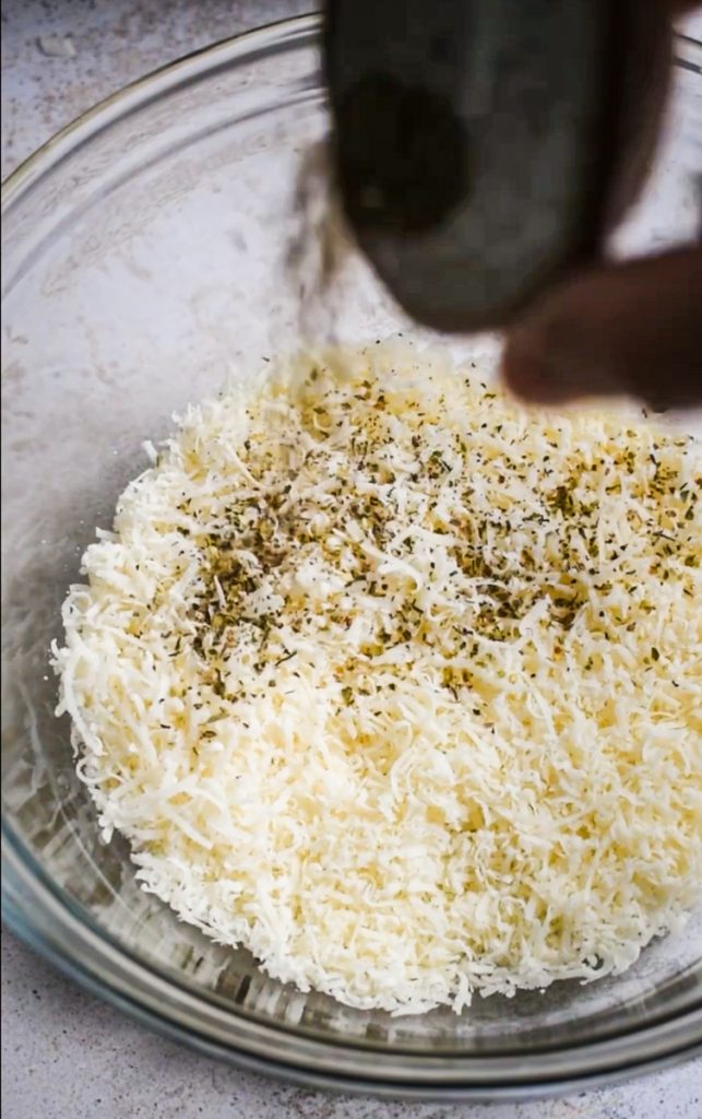Grated parmesan in a bowl with spices.