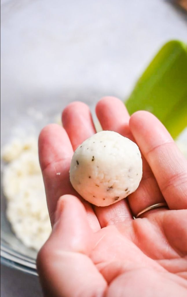 Hand holding a polpette di parmigiano before it is fried.