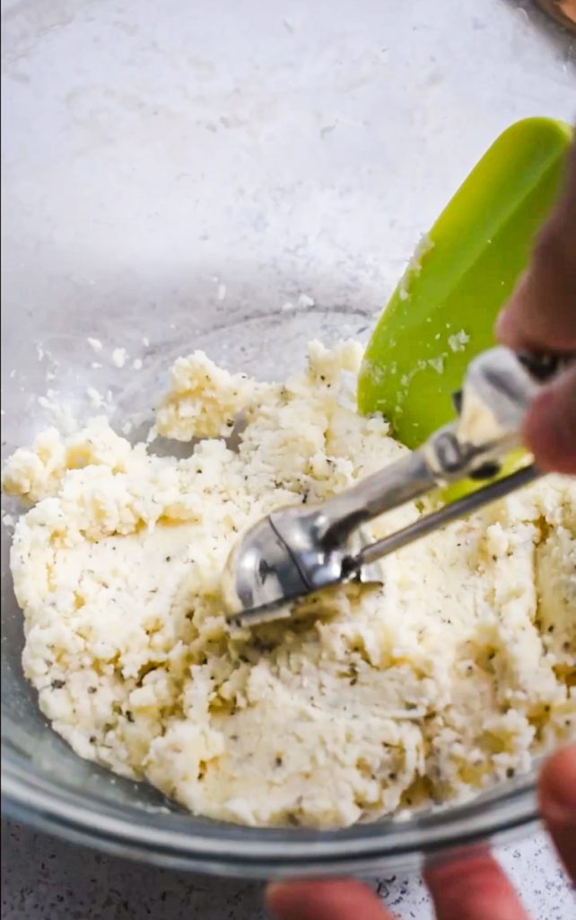 Using a cookie scoop to shape the polpette de parmigiano.