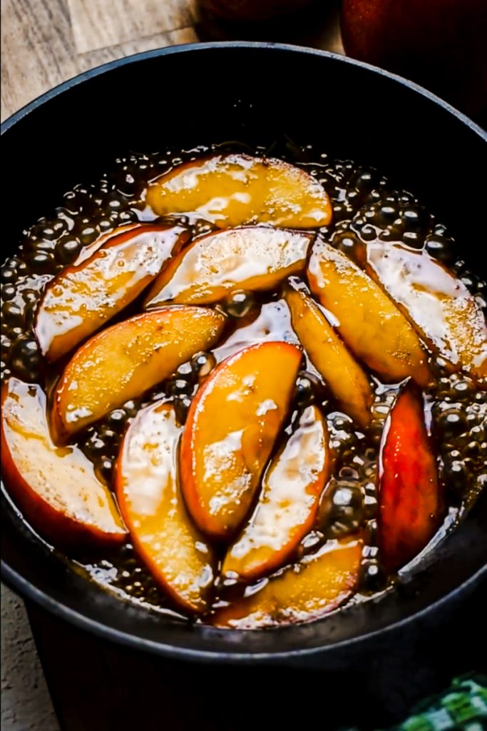 Apples flambé simmering in a cast iron skillet.