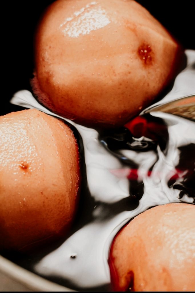Pears simmering in the red wine sauce.