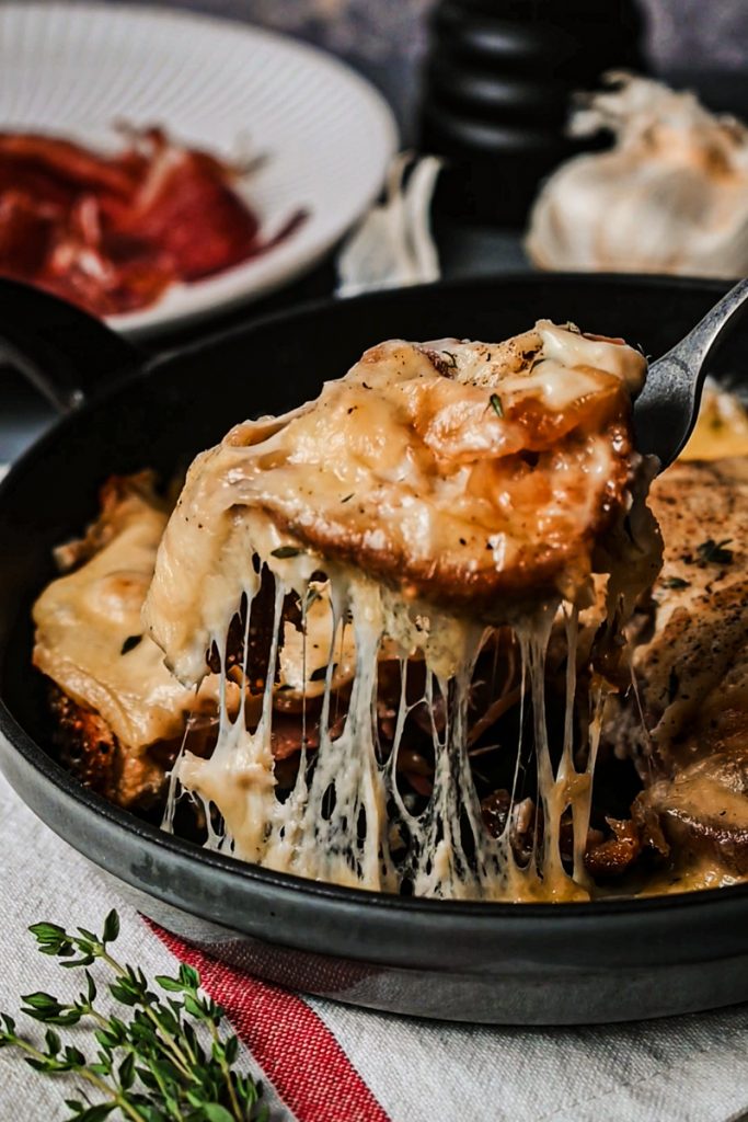Spatula lifting a piece of cheesy toast from a skillet.