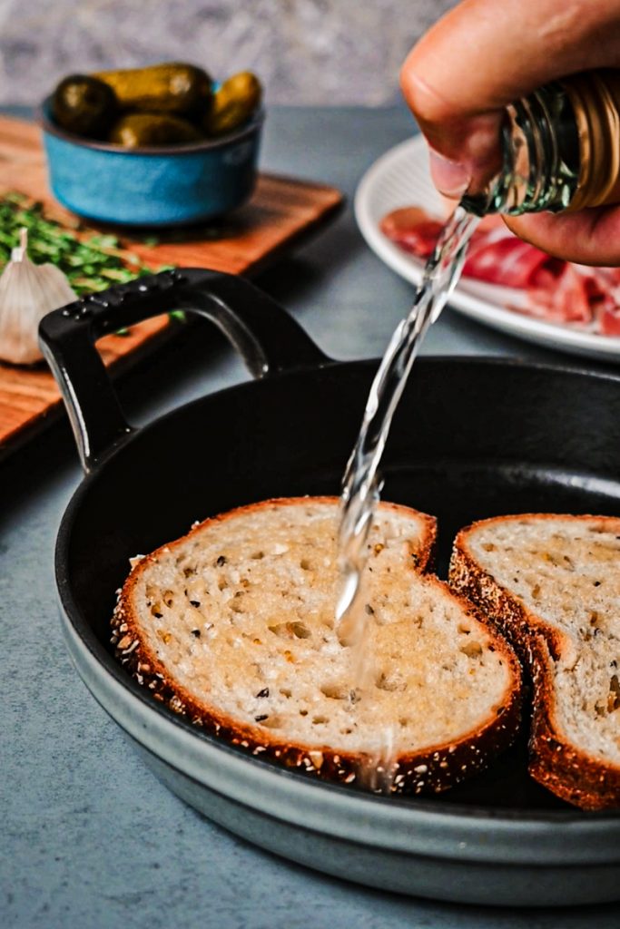 Drizzling white wine on top of bread in a skillet.