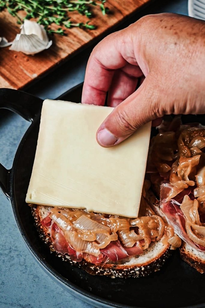 Topping the croute au fromage with slices of raclette cheese.