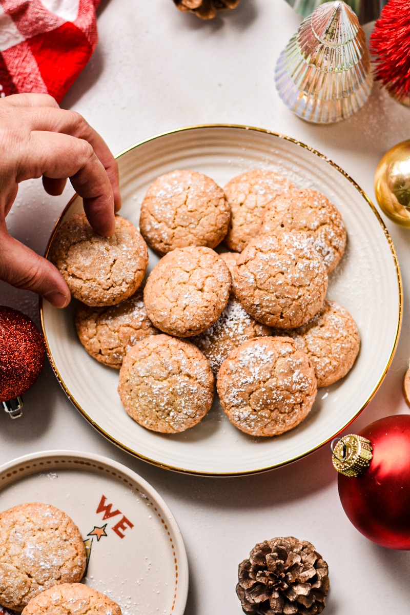 Hand taking a Macaron de Nancy from a plate.