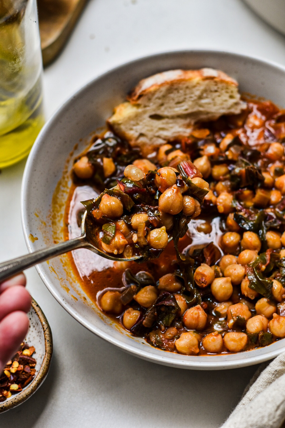 Spoon scooping up a bite of chickpea and Swiss chard soup from a bowl.