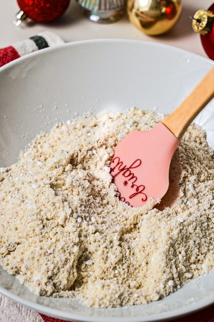 Dry ingredients in a bowl with a rubber spatula.