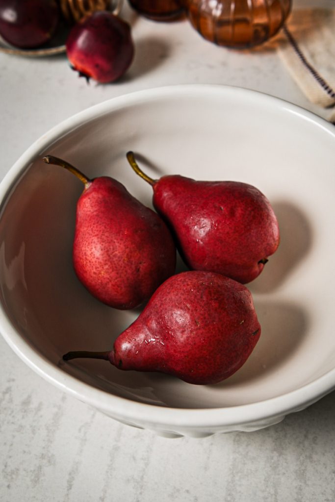 Three red pears in a white bowl.