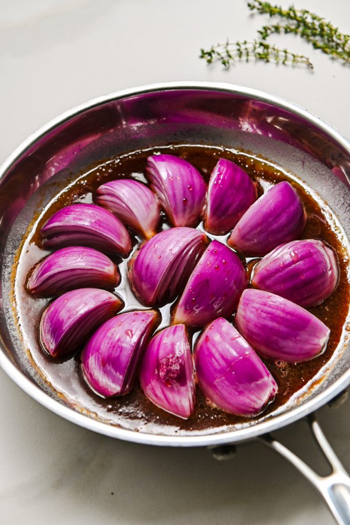 Red wine and red wine vinegar in a skillet with the red onion wedges.