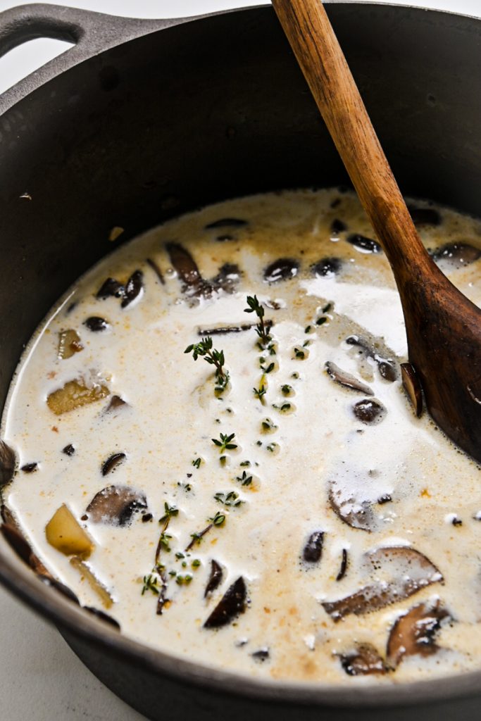 Liquids and thyme added to the soup pot with onions, mushrooms and potatoes.