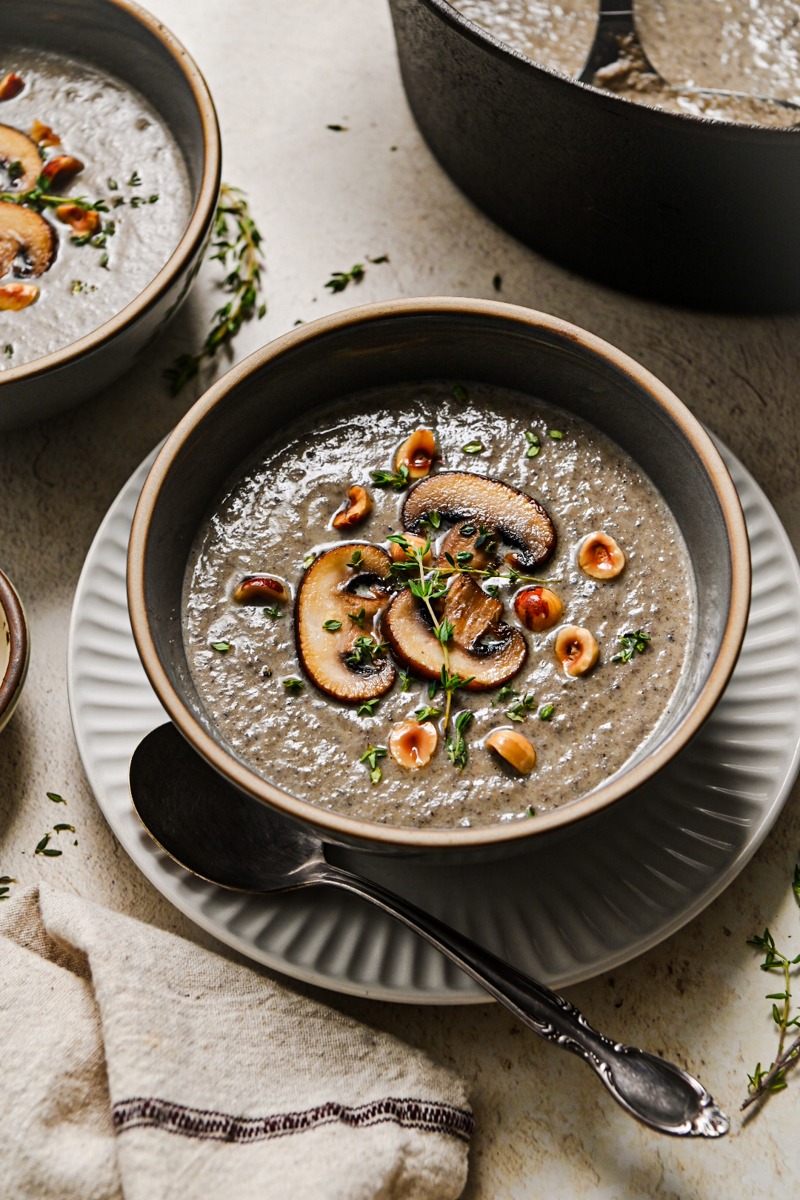 Bowl of creamy mushroom soup served on a plate with a spoon.