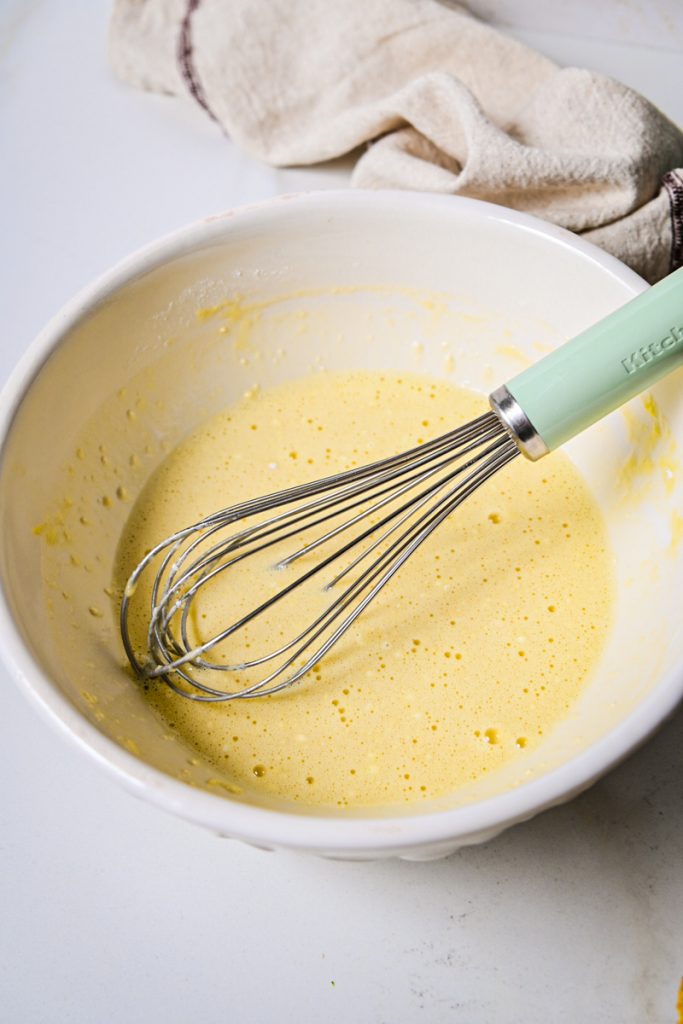 Eggs and milk whisked together in a bowl.
