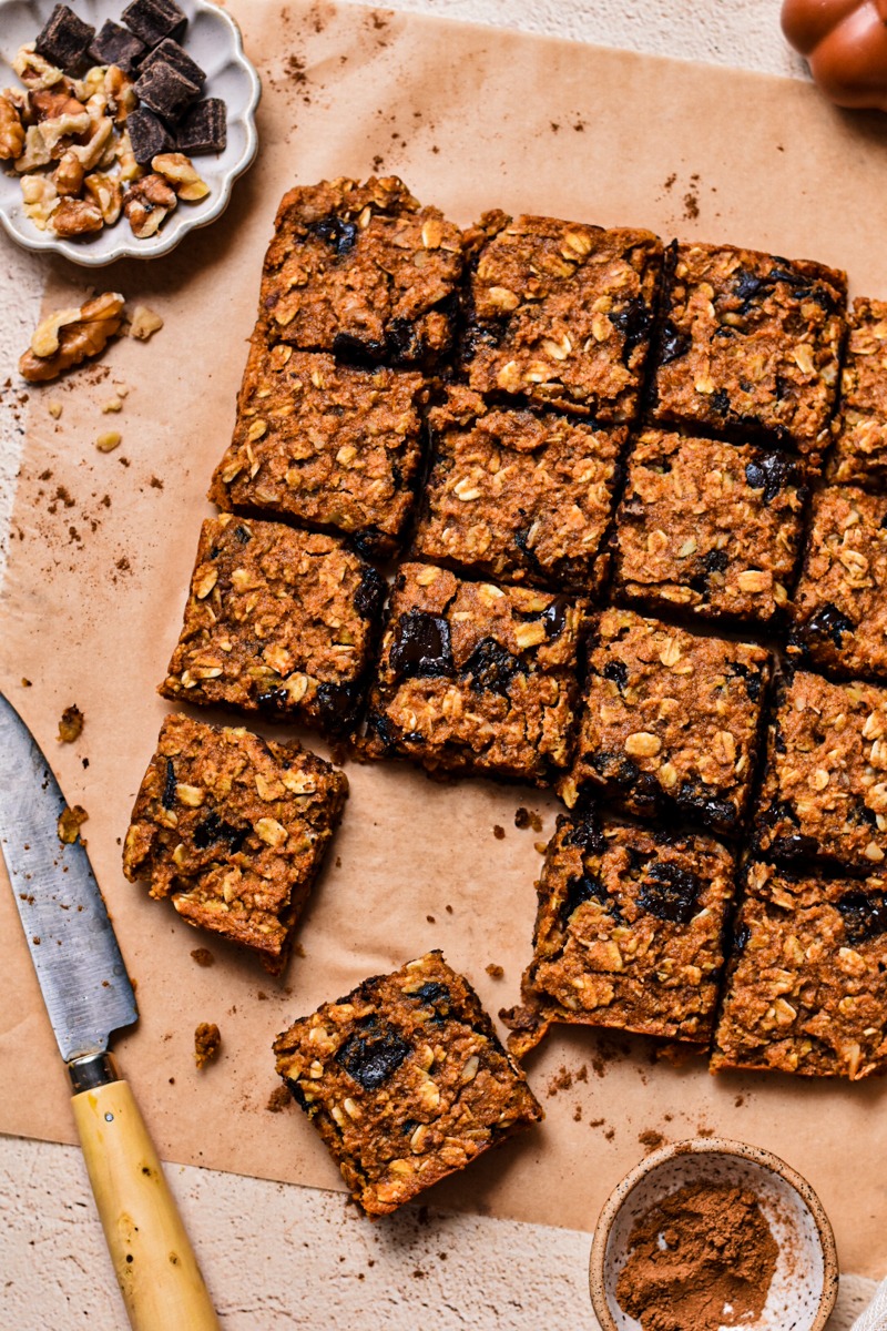 Close up of pumpkin chocolate baked oats sliced into squares on a parchment paper.
