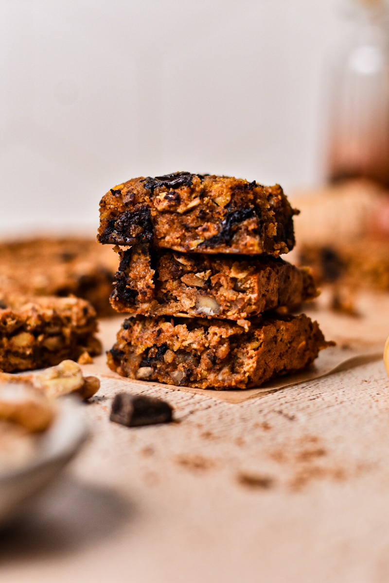 Side view of pumpkin chocolate baked oat squares stacked on top of eachother.