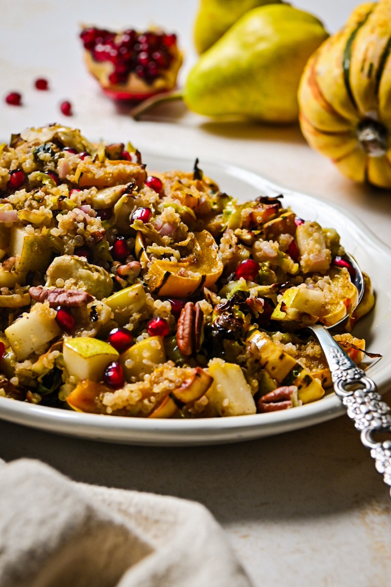 Side view of fall quinoa salad on a serving platter with a serving spoon.