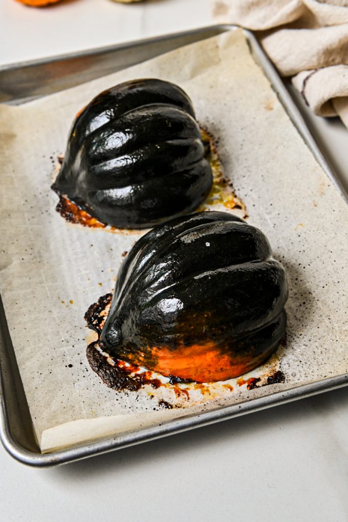 Acorn squash cut side down on a sheet pan after being roasted.