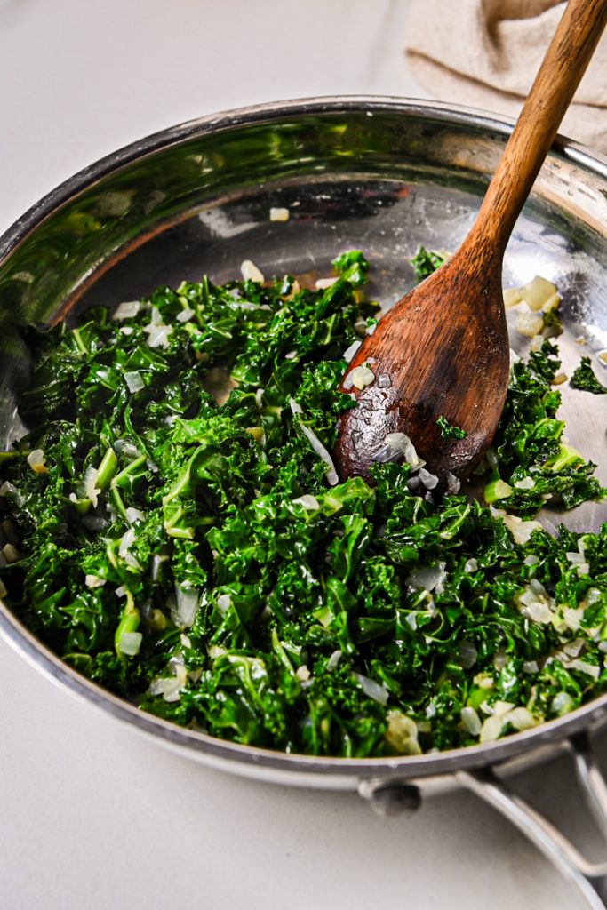 Kale, onions and garlic cooking in a skillet.