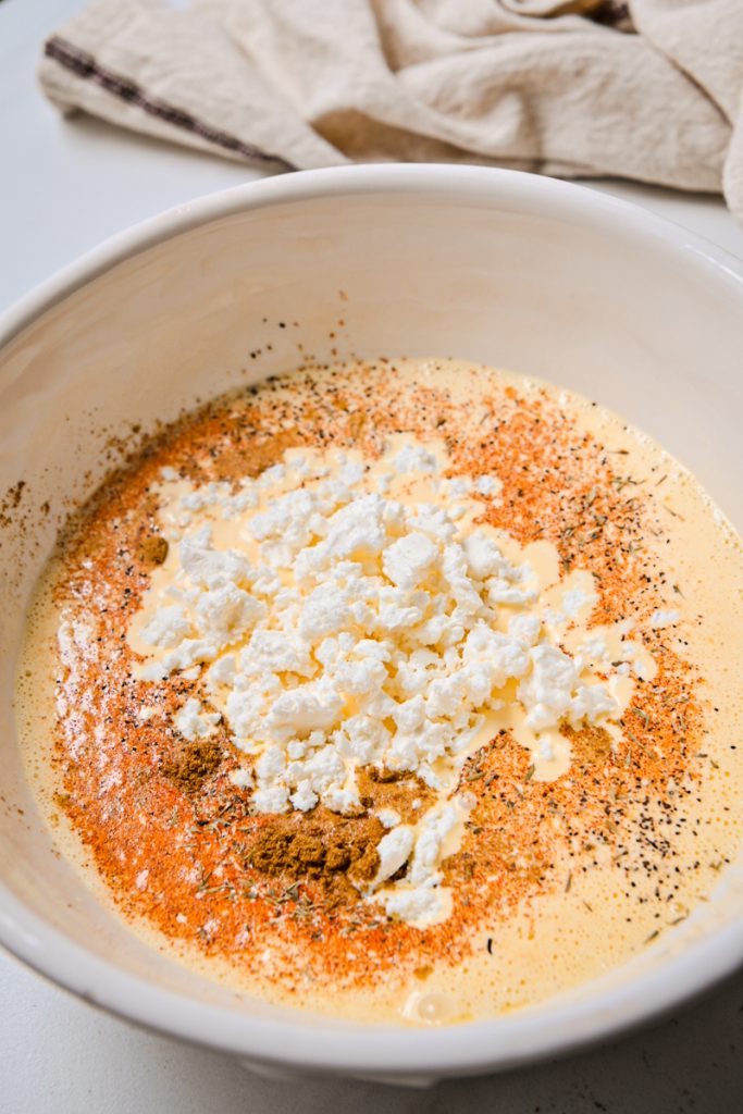 Eggs mixed with spices and feta cheese in a bowl.